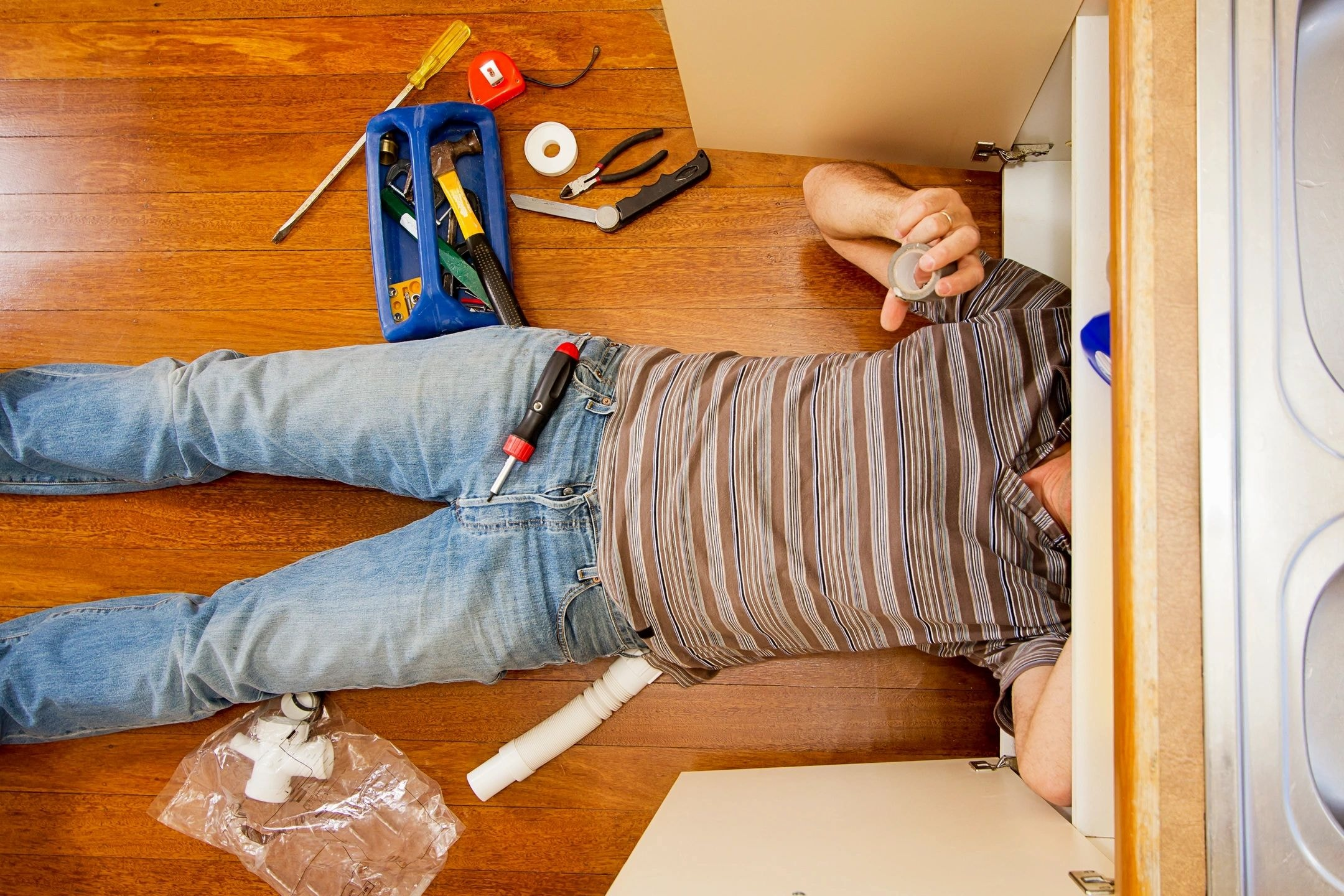 Plumber working beneath a bathroom sink